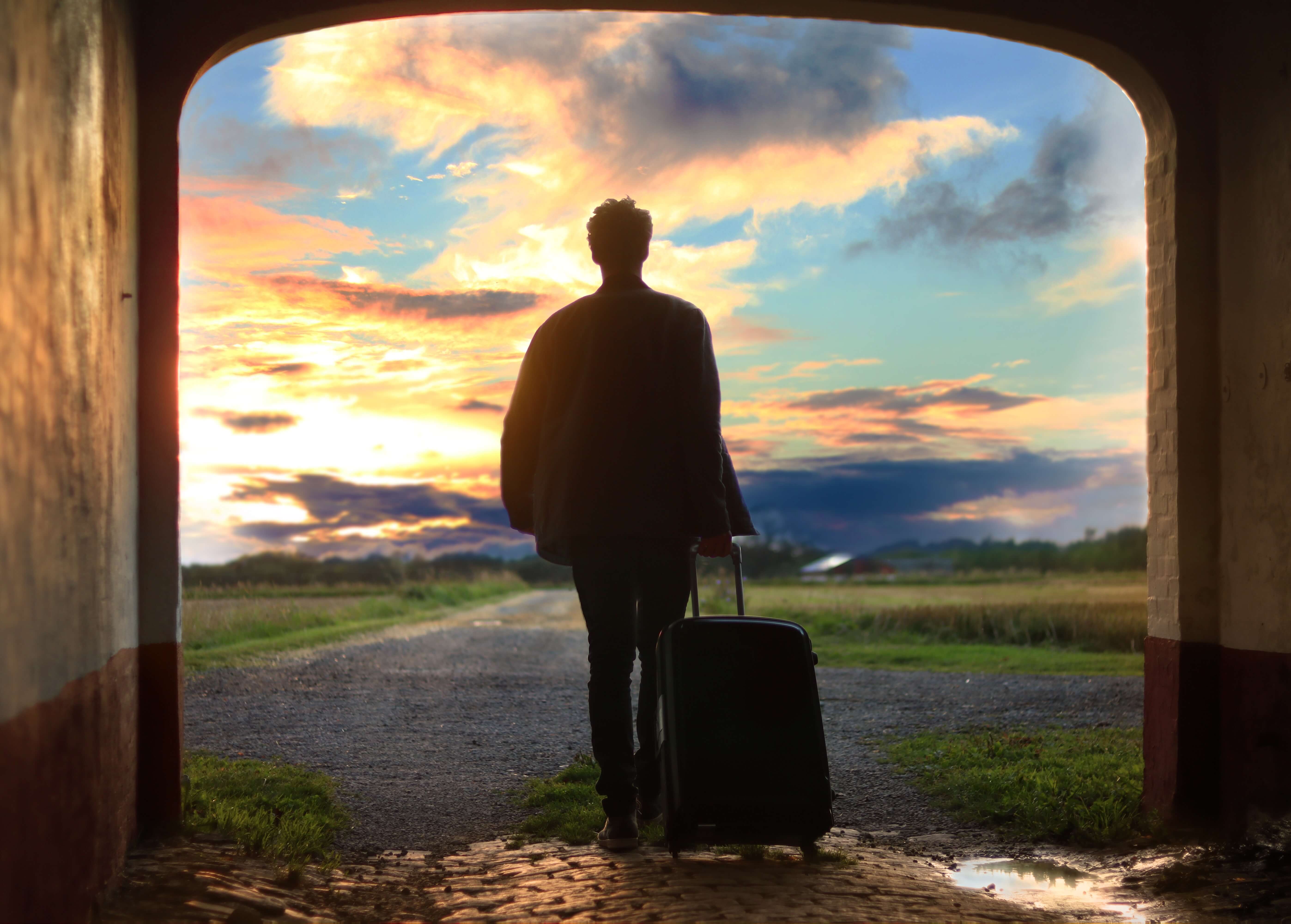A man with a suitcase heading off into the horizon